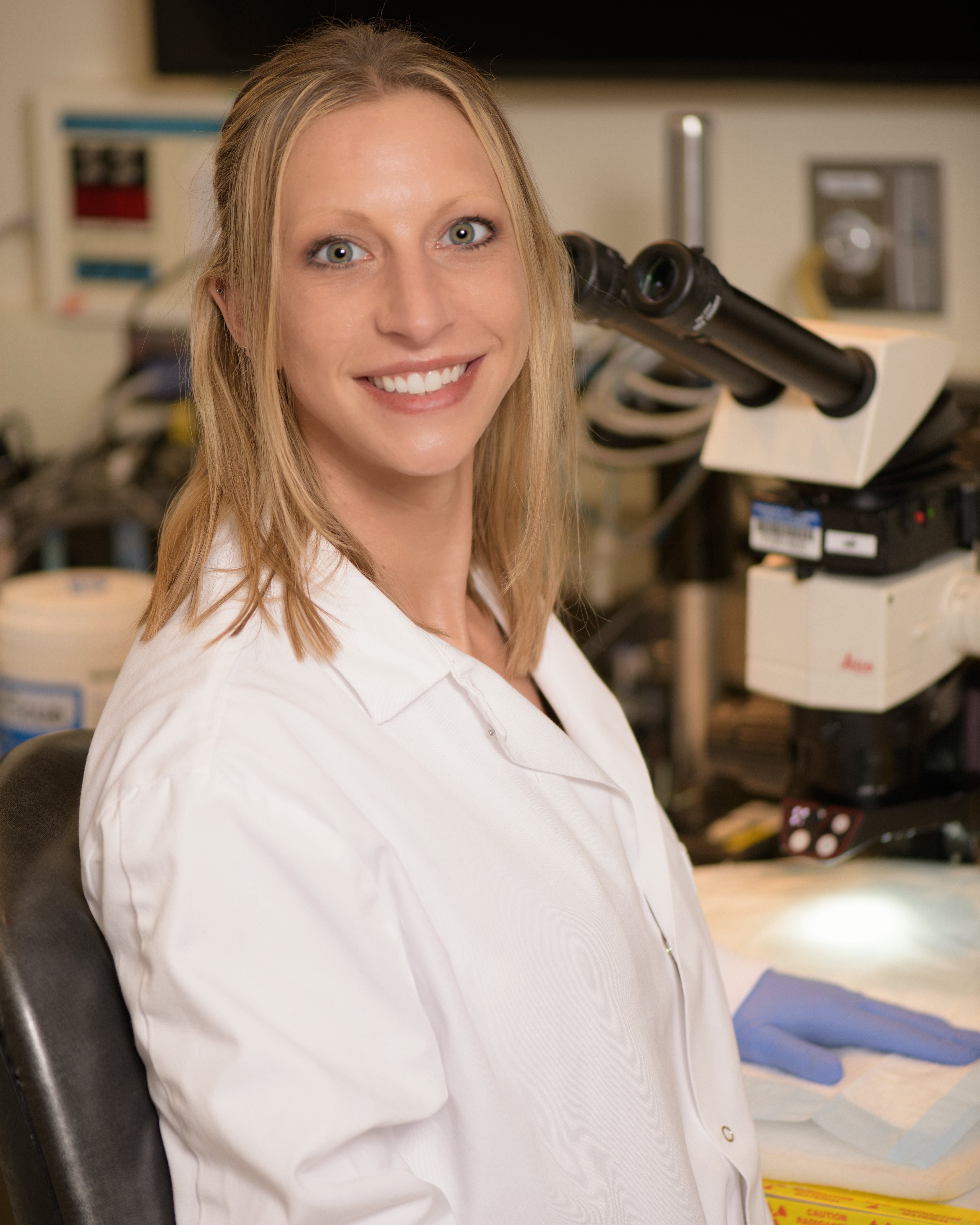 Applegate smiles by a microscope.
