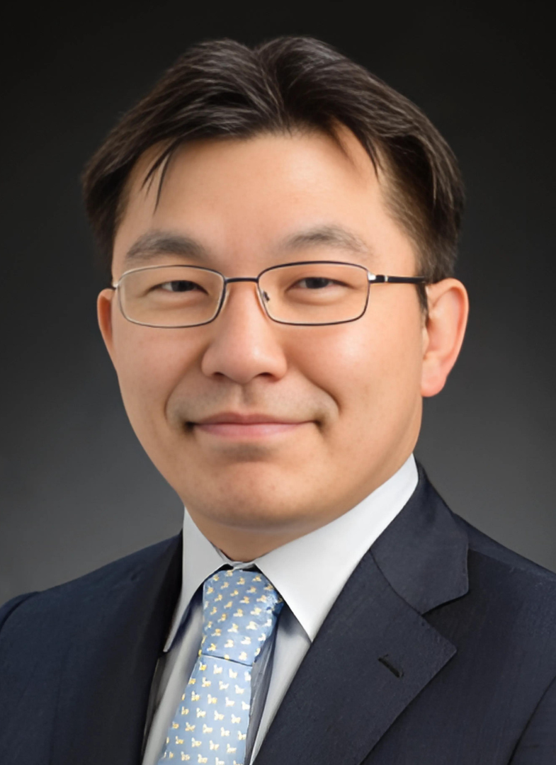 Professor Hyunjoon Kong smiles at the camera, wearing glasses and a blue tie.