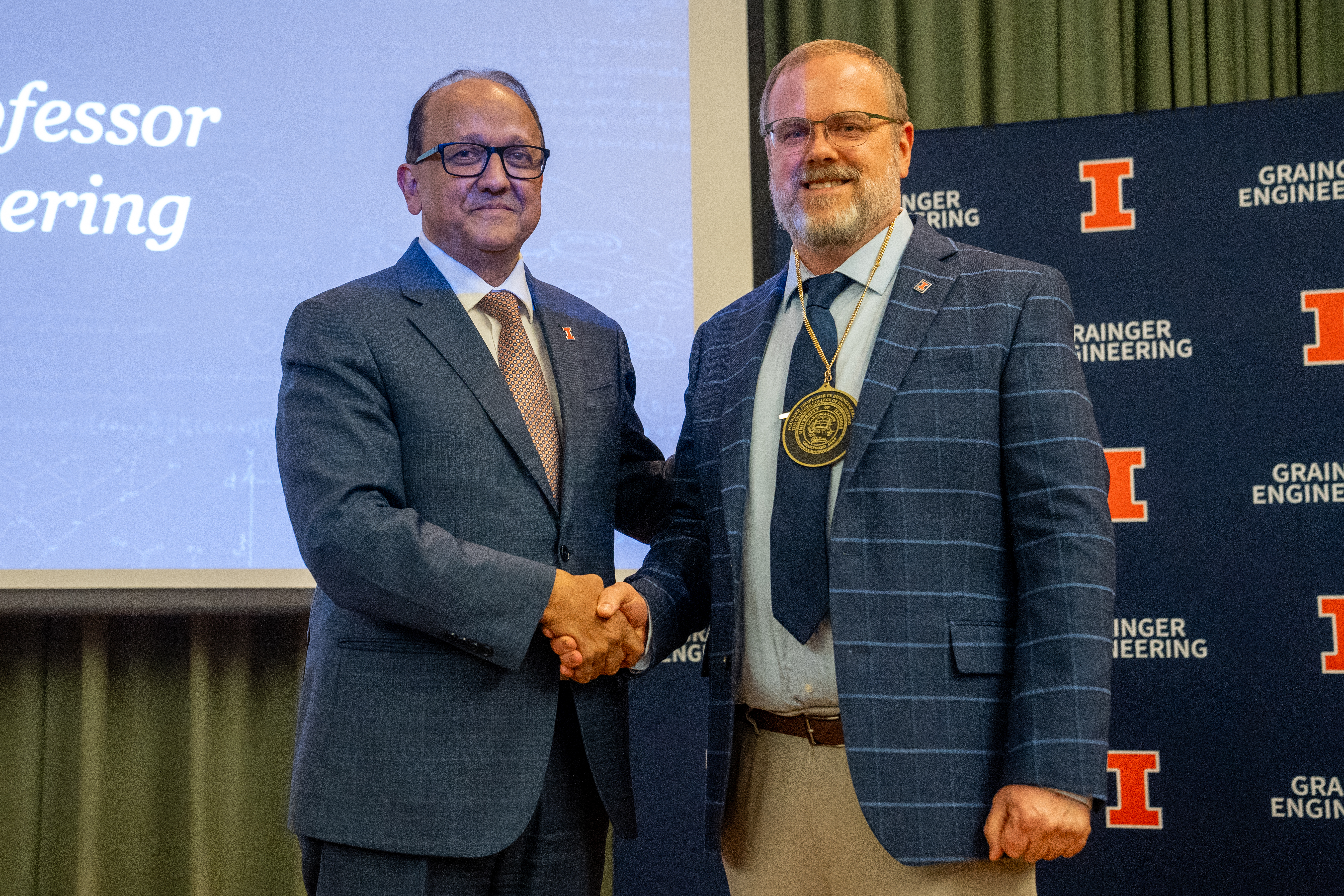 Two men stand shaking hands