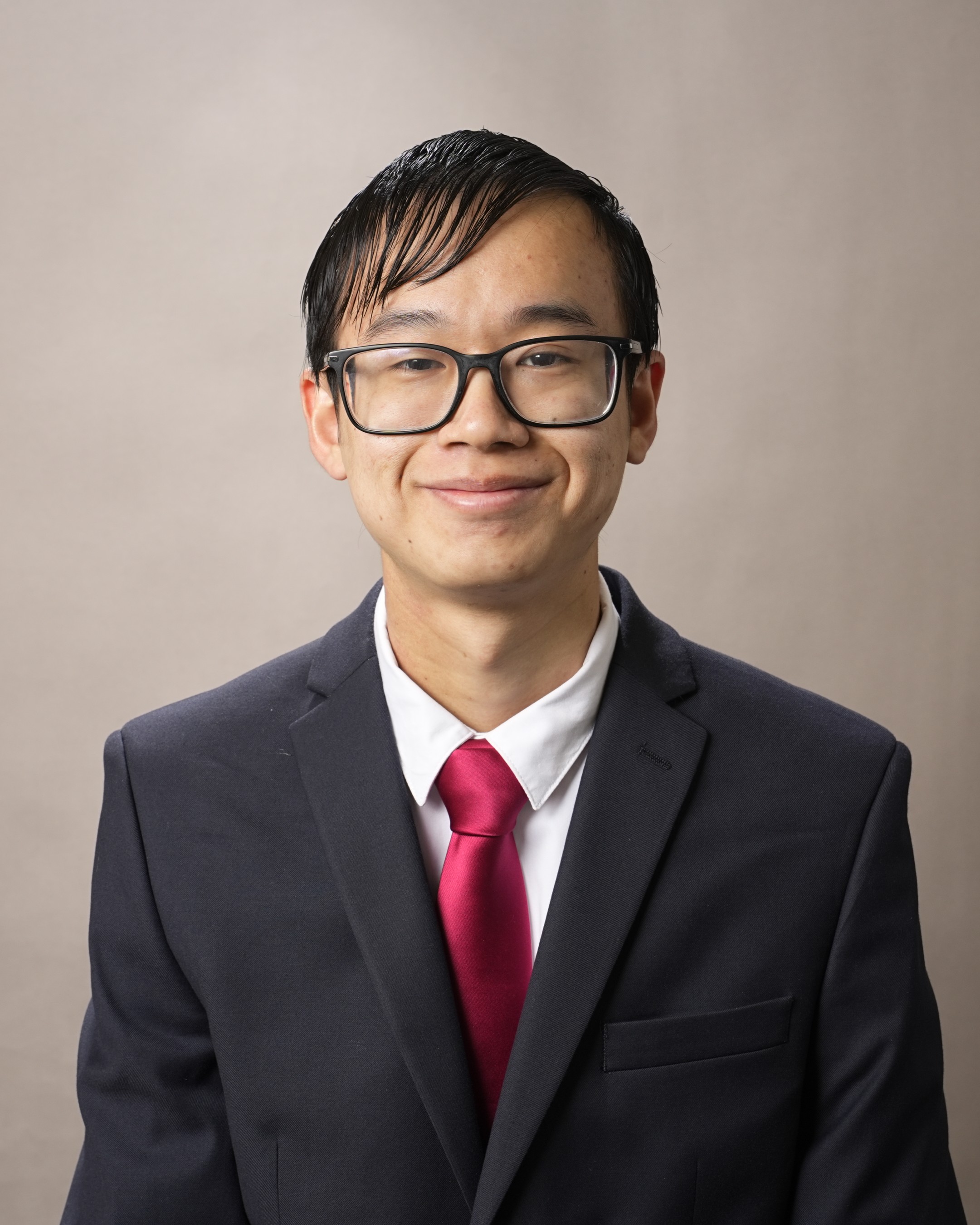 A student smiles at the camera in front of a brown background.