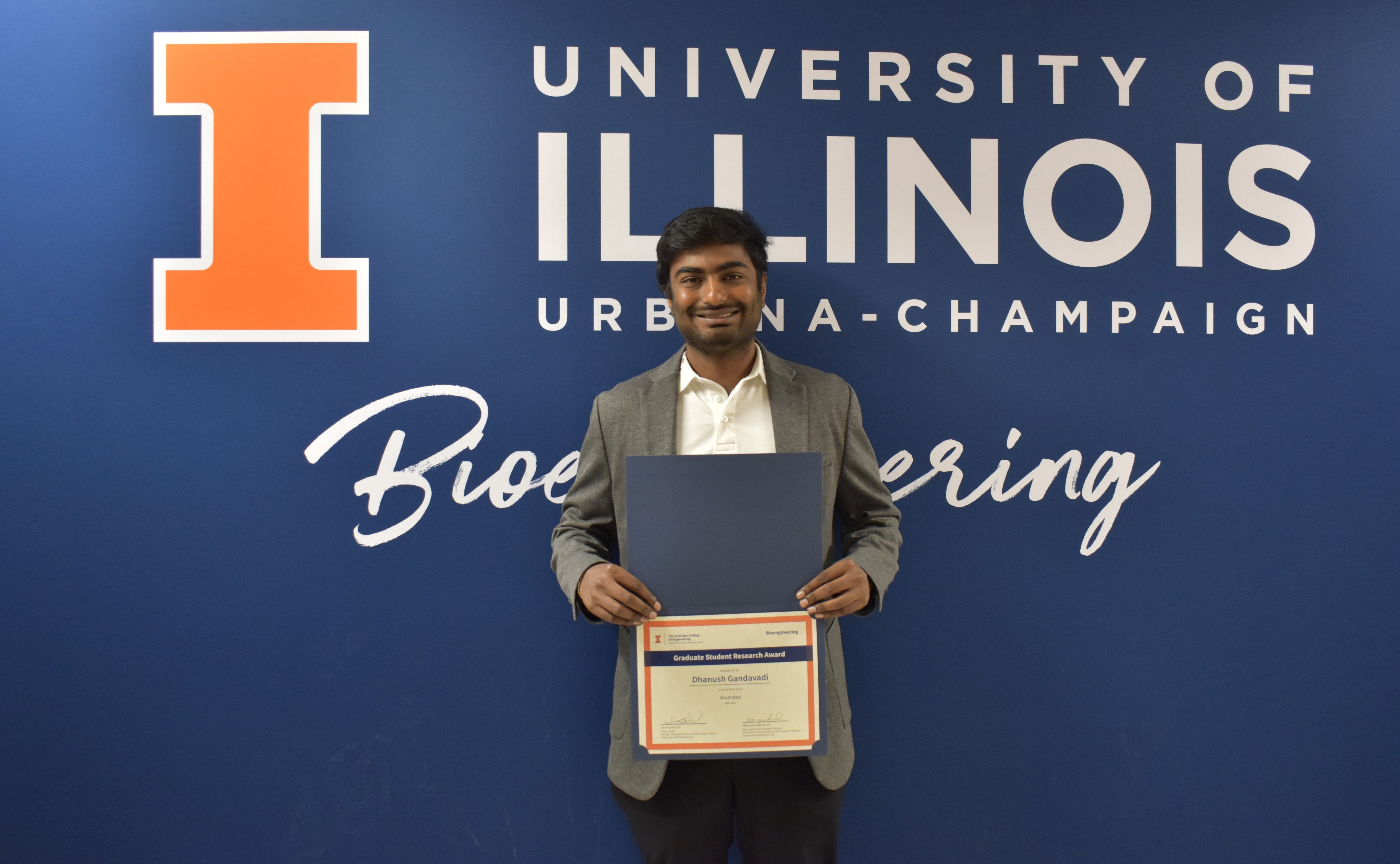 A student smiles while holding a certificate.