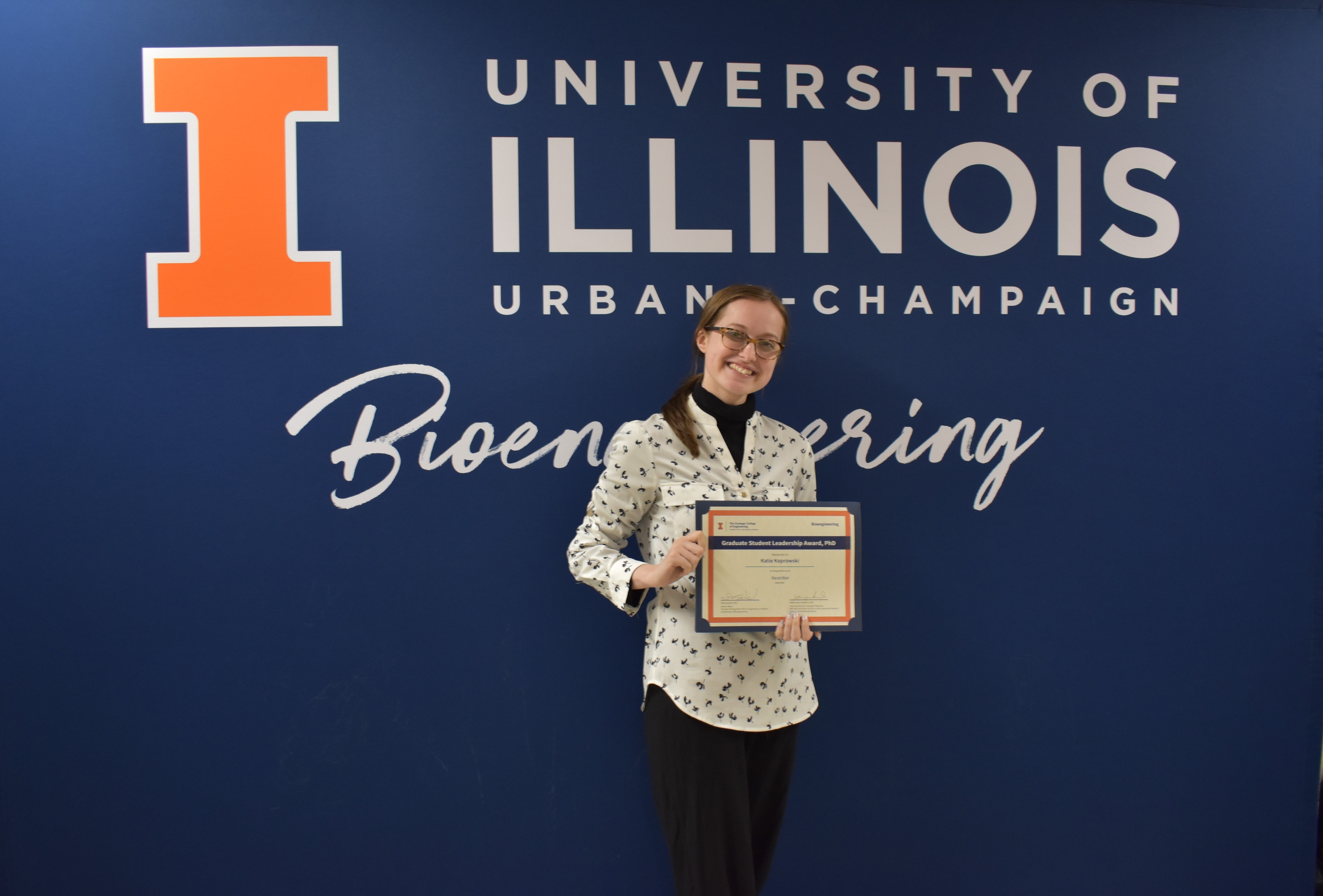 A student smiles while holding a certificate.