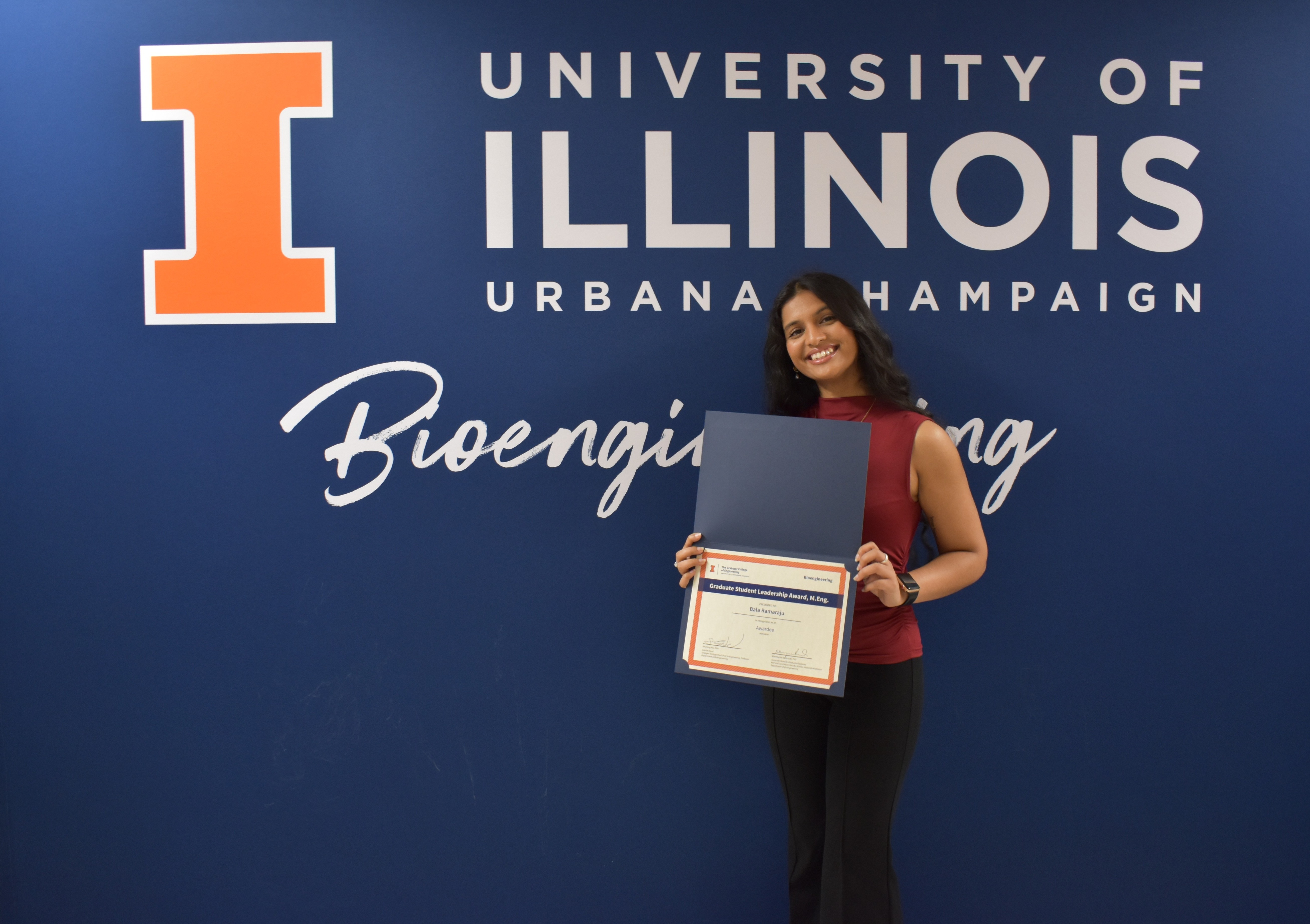 A student smiles while holding a certificate.