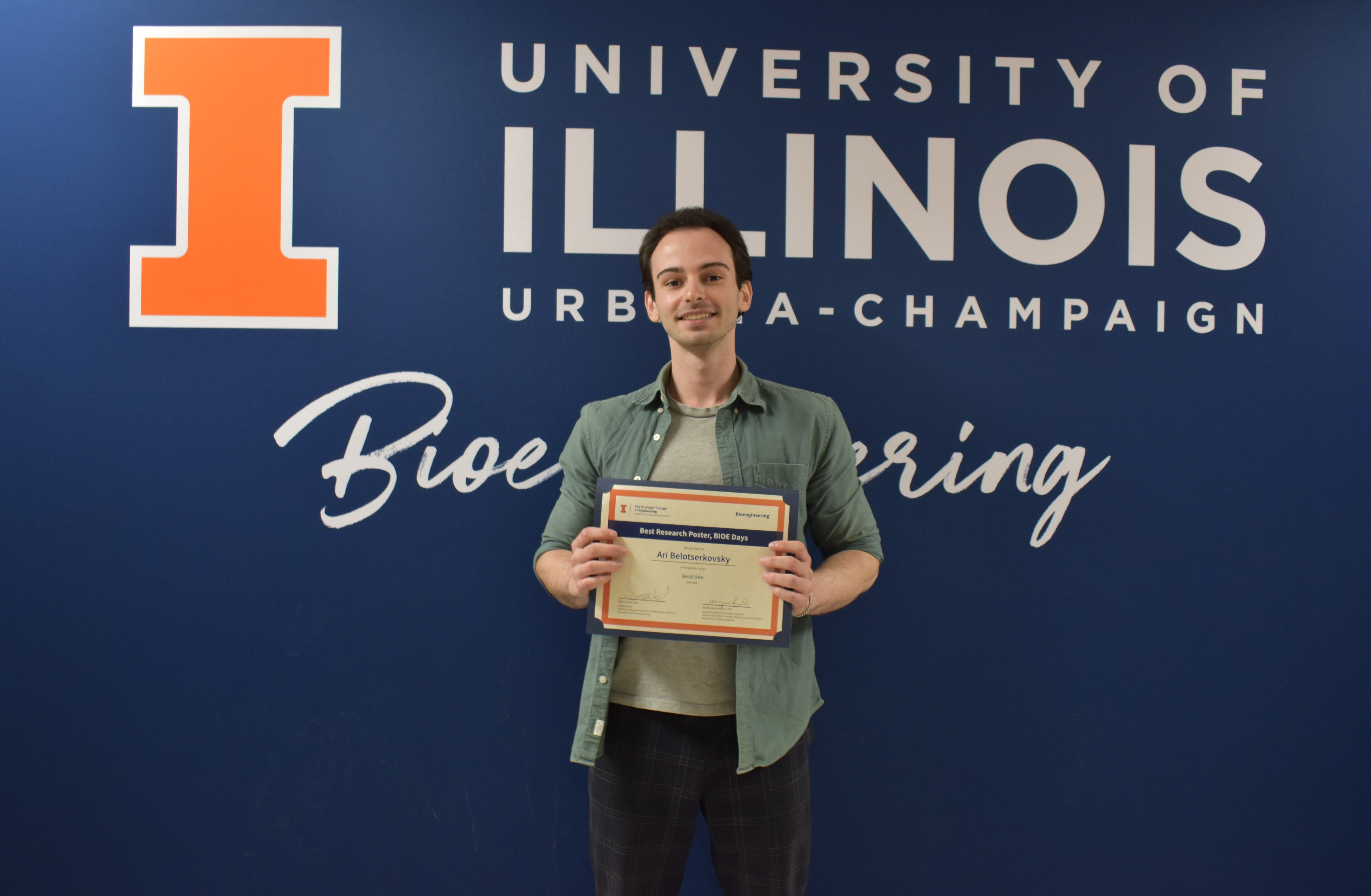 A student smiles while holding a certificate.
