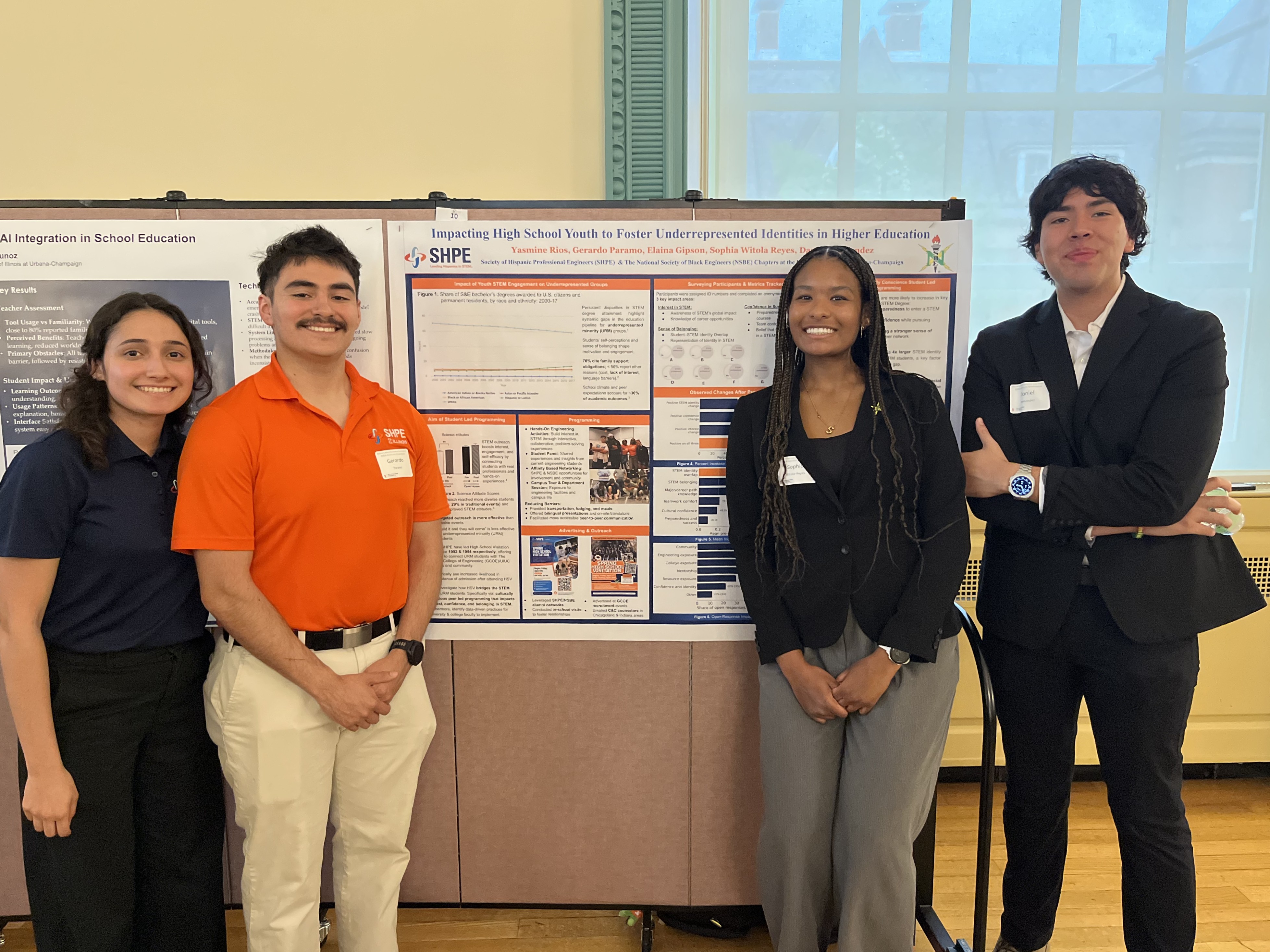 Four students stand in front of their research poster and smile