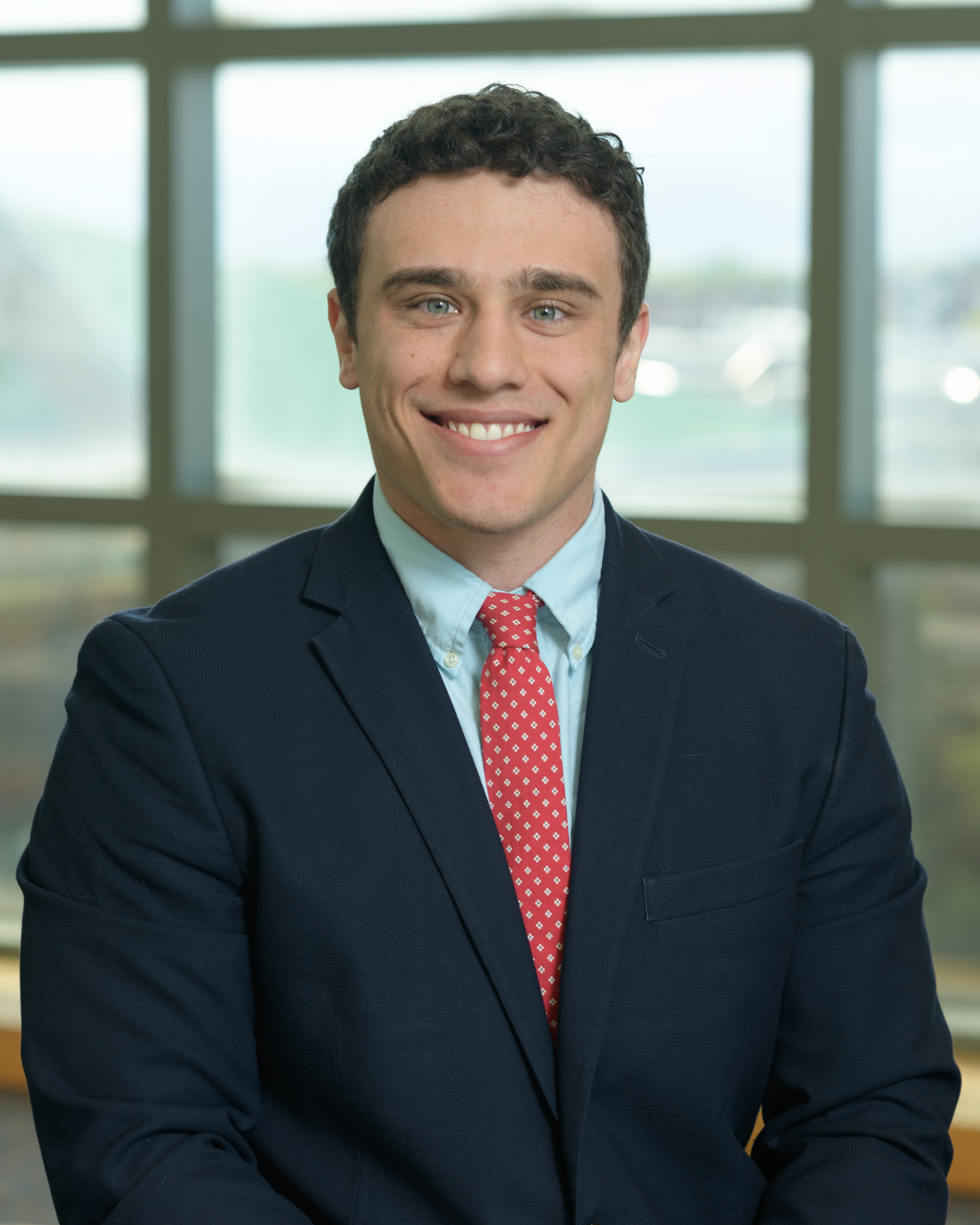 A man with a red tie smiles at the camera