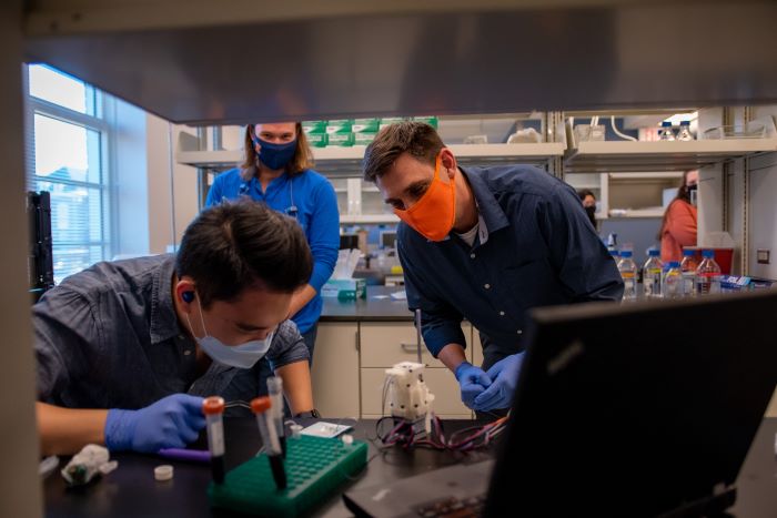 Underhill works in his lab with Illinois graduates Hyeon Ryoo (front) and Aidan Brougham-Cook (back). 