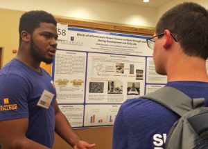 male student explaining research poster