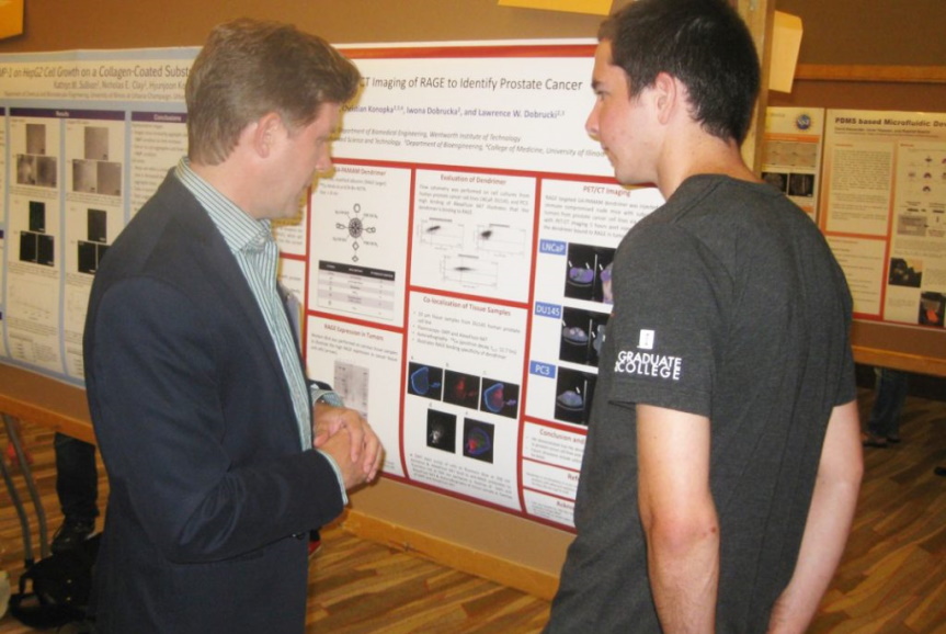 Two men stand in front of research poster