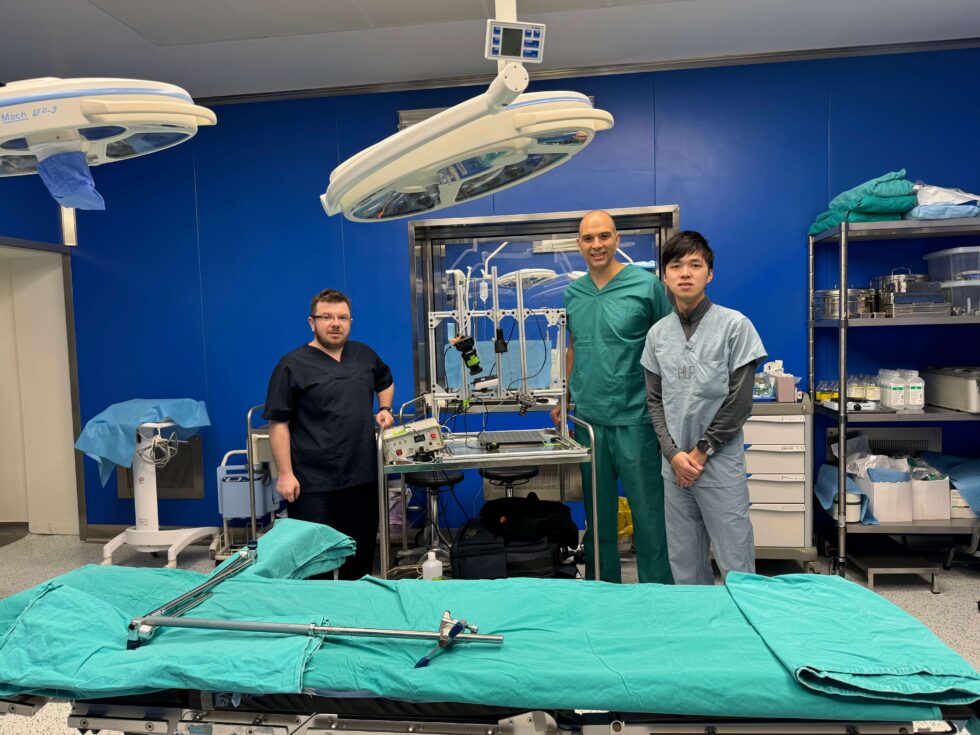 <em>Left to right: Prof. Borislav Kondov, Viktor Gruev, and Zhongmin Zhu, shown here in the operating room at the University Clinic Hospital in North Macedonia along with the NSF-funded research team&rsquo;s imaging instrument which allows for evaluation of ex vivo samples taken during surgery and evaluation of the presence of metastatic lymph nodes.</em>&nbsp;